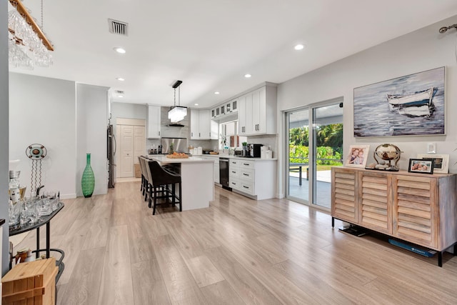 kitchen featuring a breakfast bar, pendant lighting, refrigerator, white cabinetry, and a center island