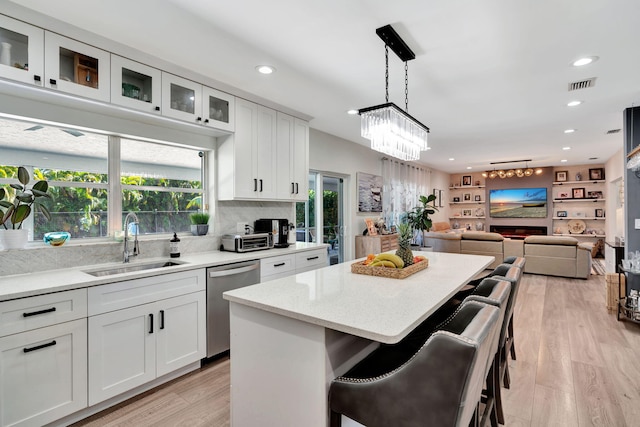 kitchen with a breakfast bar area, white cabinetry, hanging light fixtures, a center island, and stainless steel dishwasher