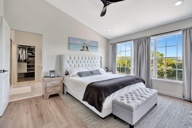 bedroom with light hardwood / wood-style flooring, multiple windows, vaulted ceiling, and a spacious closet