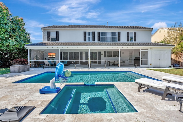 back of house featuring a swimming pool with hot tub, a patio, and a sunroom