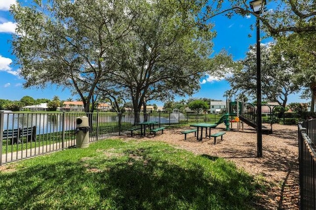 view of home's community with a water view, a playground, and a lawn