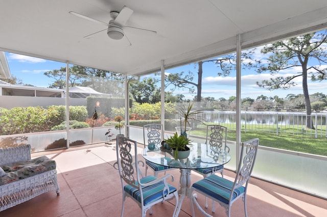 sunroom / solarium featuring a healthy amount of sunlight, ceiling fan, and a water view