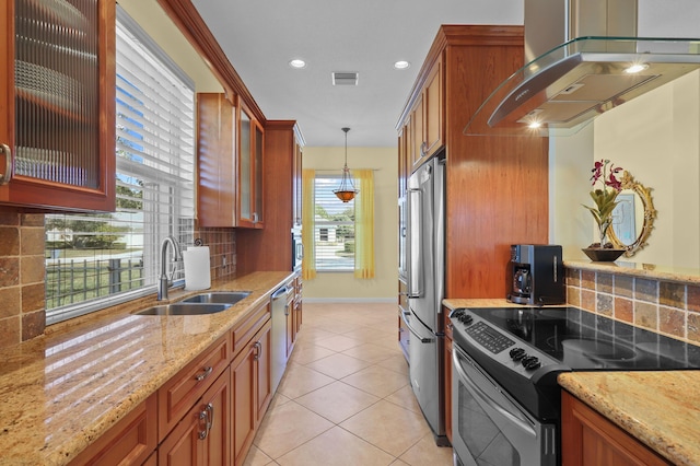 kitchen featuring sink, appliances with stainless steel finishes, hanging light fixtures, light stone countertops, and island exhaust hood