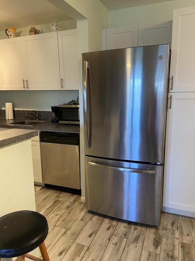 kitchen featuring stainless steel appliances, sink, white cabinets, and light wood-type flooring