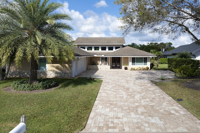 view of front of property with an attached garage, a front yard, decorative driveway, and french doors