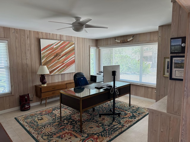 office space with light tile patterned flooring, ceiling fan, and wooden walls