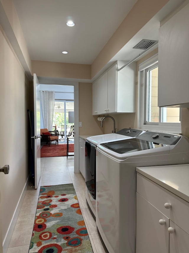 washroom with cabinets, light tile patterned flooring, and washing machine and clothes dryer