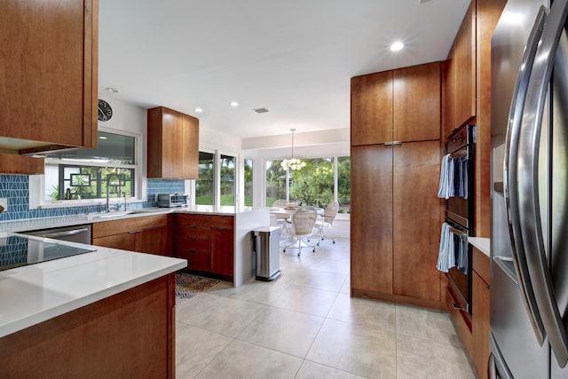 kitchen featuring decorative light fixtures, stainless steel fridge, backsplash, kitchen peninsula, and a healthy amount of sunlight