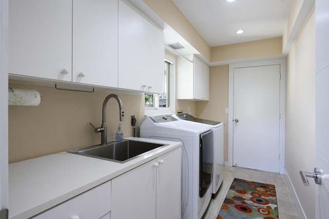 washroom with cabinets, light tile patterned floors, sink, and washing machine and clothes dryer