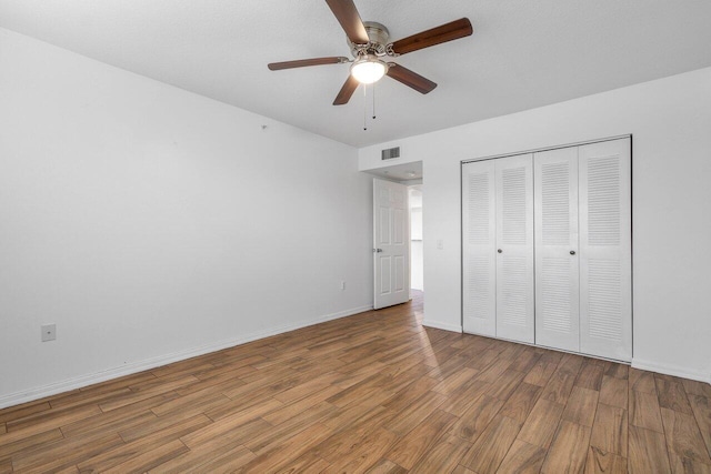 unfurnished bedroom featuring hardwood / wood-style flooring, a closet, and ceiling fan