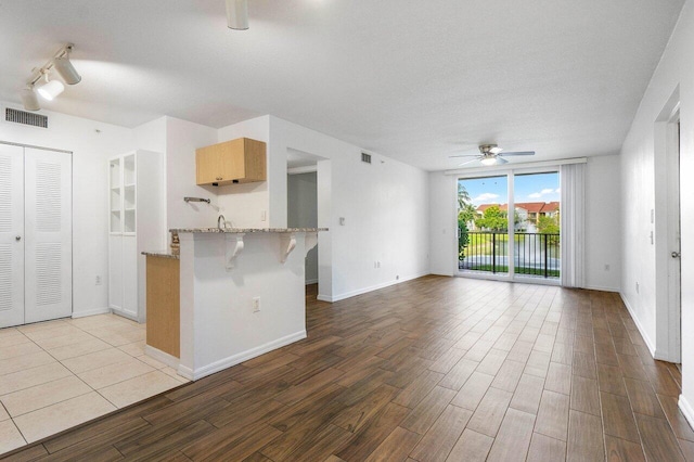 kitchen with ceiling fan, light hardwood / wood-style flooring, a kitchen bar, and kitchen peninsula