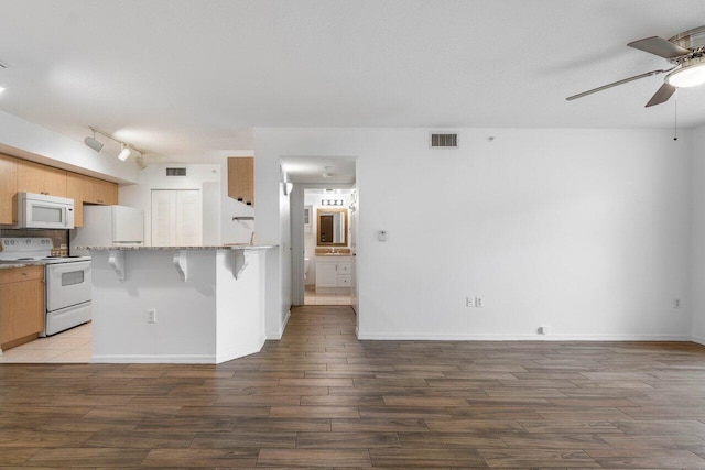 kitchen with a kitchen breakfast bar, ceiling fan, white appliances, and light hardwood / wood-style flooring