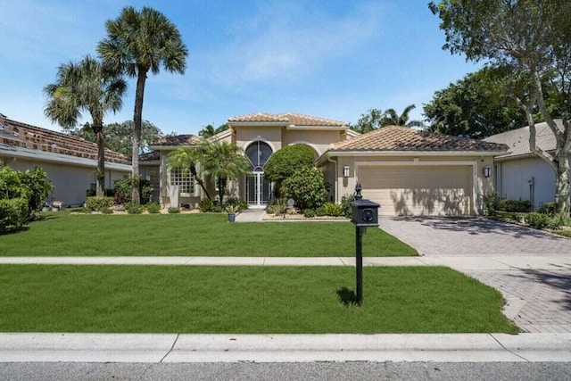 mediterranean / spanish house featuring a garage and a front yard