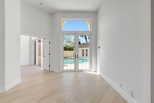 spare room featuring light hardwood / wood-style floors, french doors, and a high ceiling