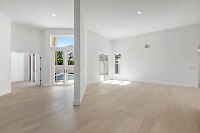 spare room with light hardwood / wood-style floors, french doors, and a high ceiling