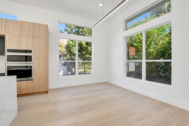 unfurnished dining area featuring a healthy amount of sunlight and light wood-type flooring