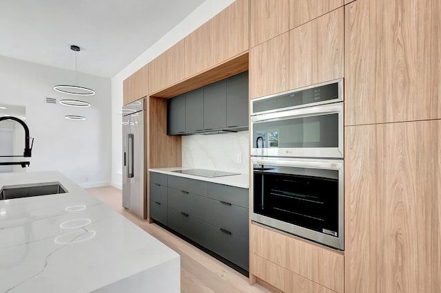 kitchen featuring appliances with stainless steel finishes, pendant lighting, sink, gray cabinetry, and light stone countertops