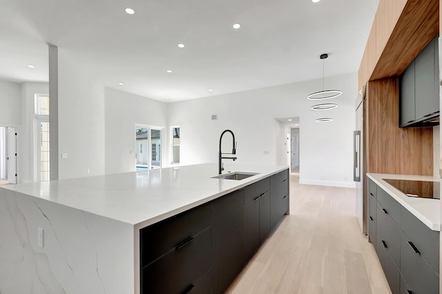 kitchen featuring sink, decorative light fixtures, light hardwood / wood-style flooring, black electric stovetop, and a large island