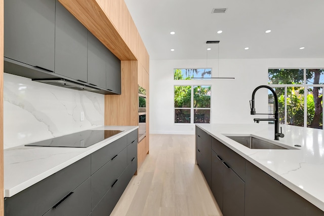 kitchen with gray cabinets, sink, backsplash, black electric stovetop, and light stone counters