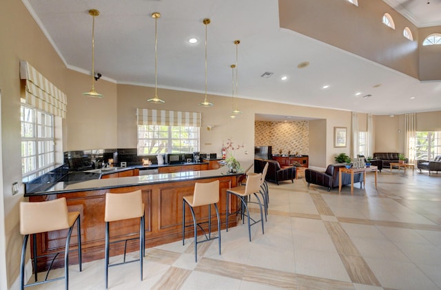 kitchen with light tile patterned floors, dishwasher, ornamental molding, a kitchen bar, and decorative light fixtures