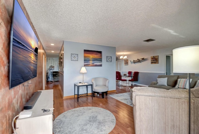 living room with an inviting chandelier, hardwood / wood-style flooring, and a textured ceiling