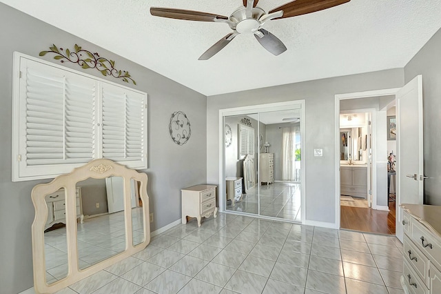 tiled bedroom with ceiling fan, a closet, and a textured ceiling