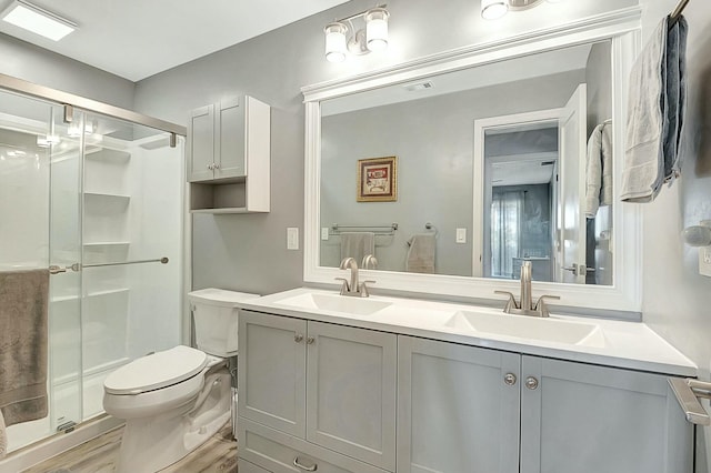 bathroom with vanity, hardwood / wood-style flooring, a shower with door, and toilet