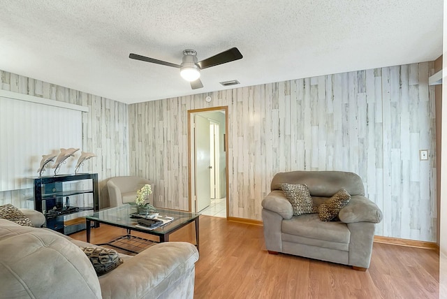 living room featuring ceiling fan, hardwood / wood-style floors, and a textured ceiling