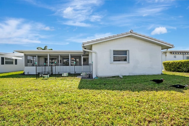 back of property with a sunroom and a lawn