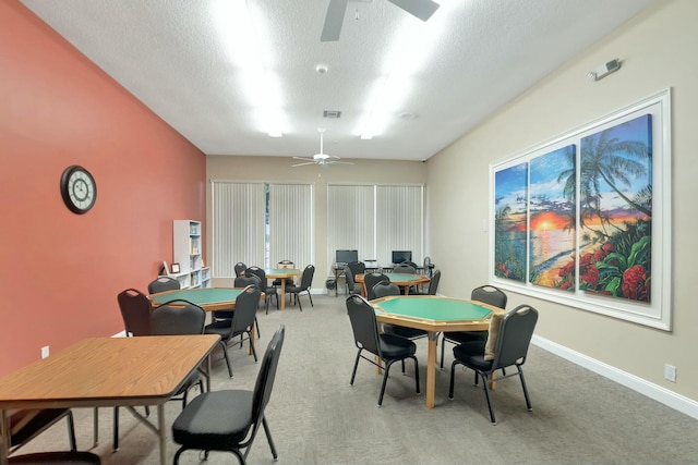 dining space with ceiling fan, light colored carpet, and a textured ceiling