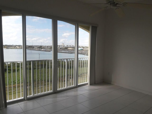 tiled spare room with a water view, plenty of natural light, and ceiling fan