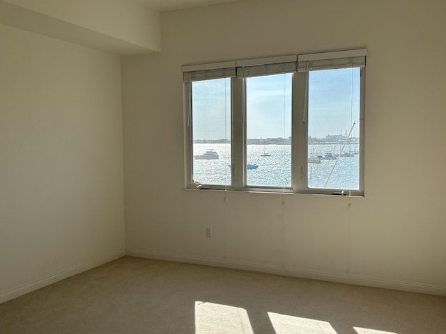 spare room featuring a water view and light colored carpet