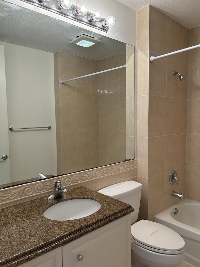 full bathroom featuring tiled shower / bath combo, vanity, a textured ceiling, and toilet