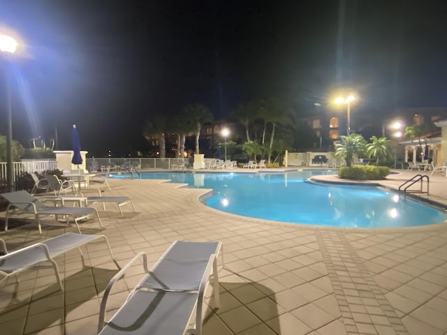 pool at night with a patio area