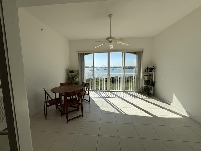 dining room with a water view, light tile patterned floors, and ceiling fan