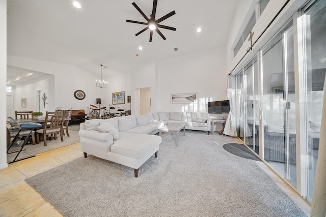 tiled living room featuring ceiling fan with notable chandelier and high vaulted ceiling