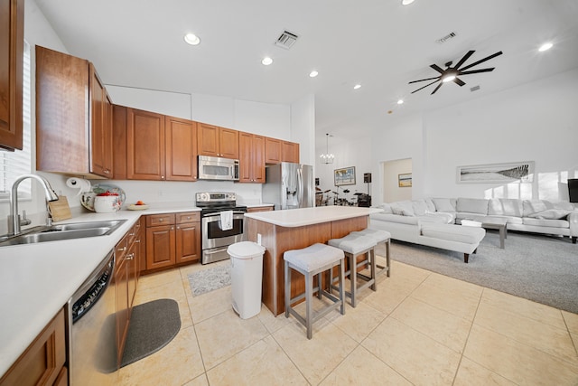 kitchen featuring sink, light tile patterned floors, appliances with stainless steel finishes, a center island, and a kitchen bar