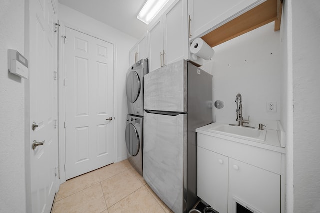 laundry area with cabinets, stacked washer / dryer, sink, and light tile patterned floors