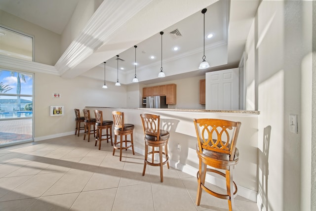 kitchen featuring decorative light fixtures, ornamental molding, stainless steel refrigerator, and kitchen peninsula