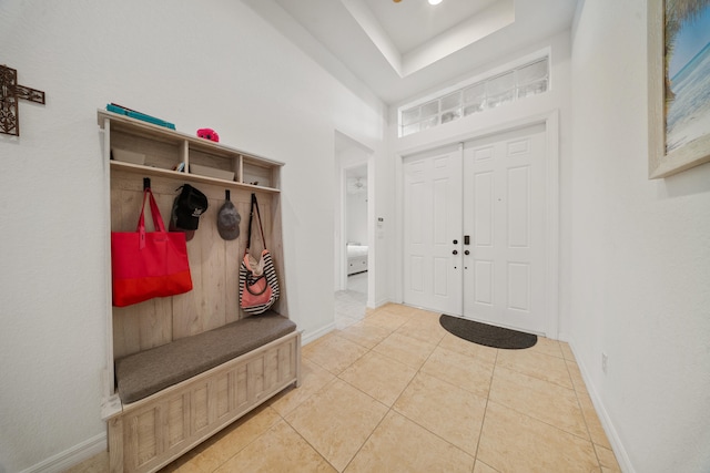 mudroom with tile patterned floors and a raised ceiling