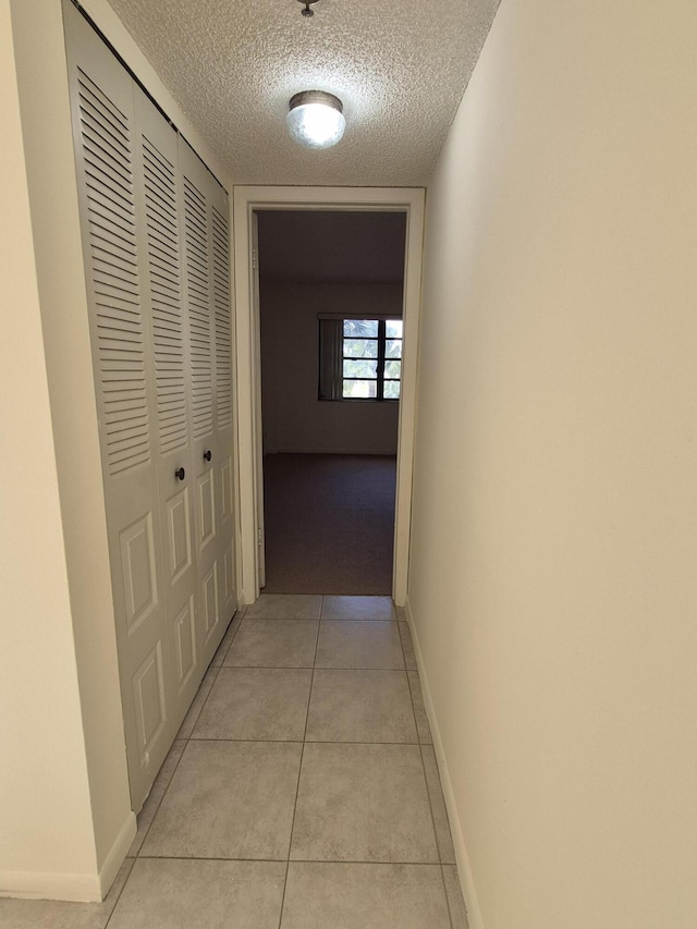 corridor featuring light tile patterned floors and a textured ceiling