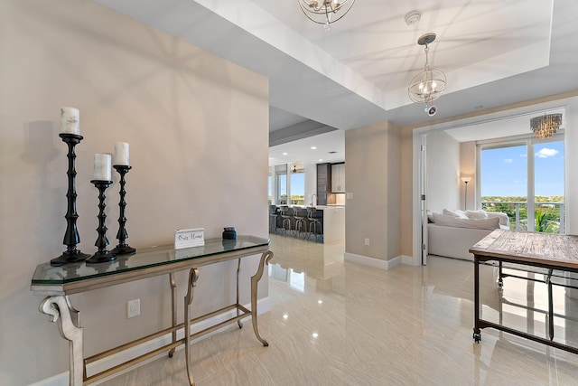 hall featuring a chandelier and a tray ceiling