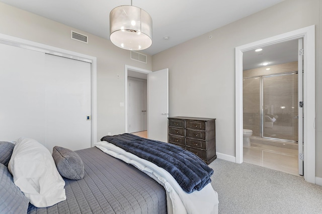 carpeted bedroom with ensuite bathroom and a closet