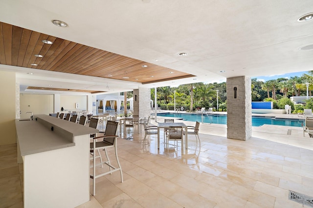 view of swimming pool featuring a bar and a patio