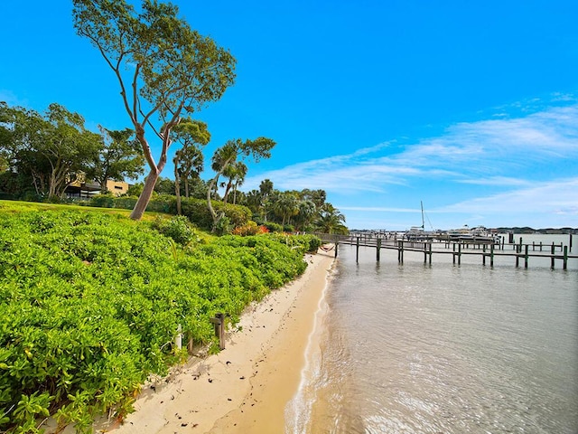 view of dock with a water view and a beach view