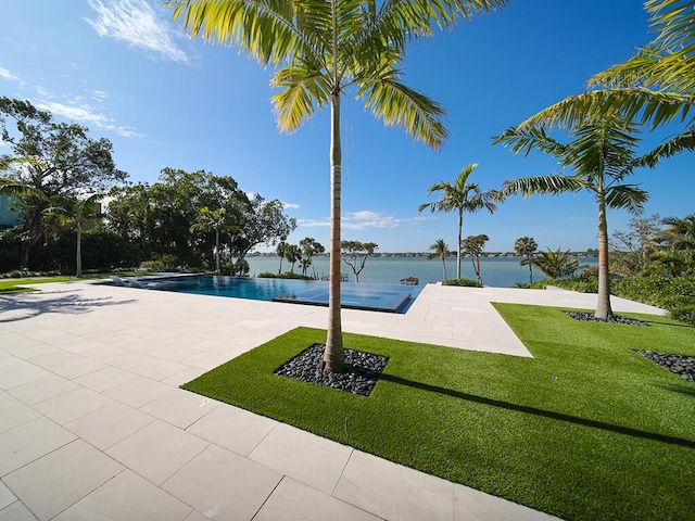 view of pool with a water view, a yard, and a patio area