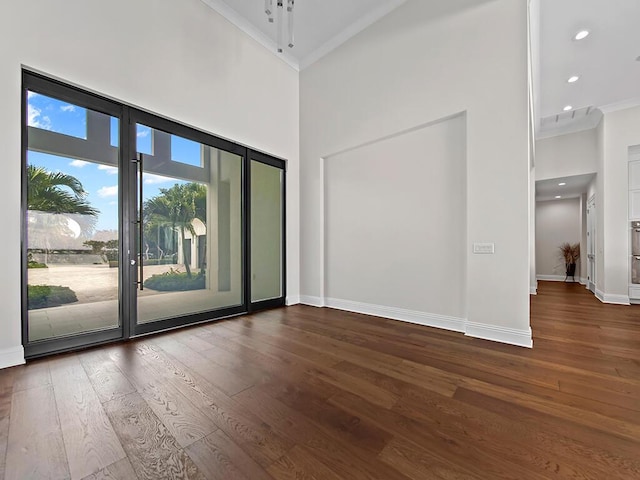 unfurnished room featuring a high ceiling, ornamental molding, and dark hardwood / wood-style flooring