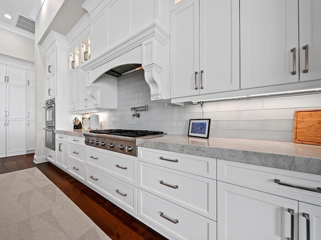 kitchen featuring dark hardwood / wood-style floors, white cabinets, stainless steel appliances, light stone countertops, and backsplash