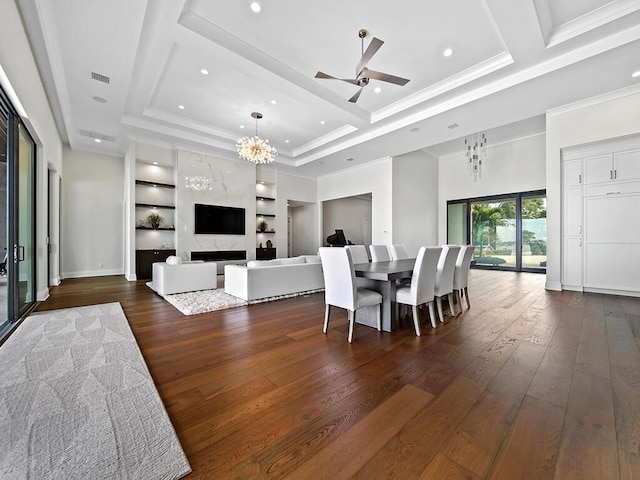 dining area with a tray ceiling, a high end fireplace, dark hardwood / wood-style floors, and built in shelves