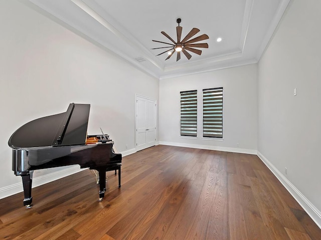 living area with crown molding, ceiling fan, a raised ceiling, and hardwood / wood-style floors